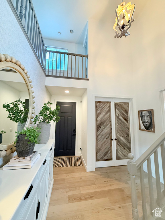 Entryway featuring a chandelier, a high ceiling, light wood-style floors, baseboards, and stairs