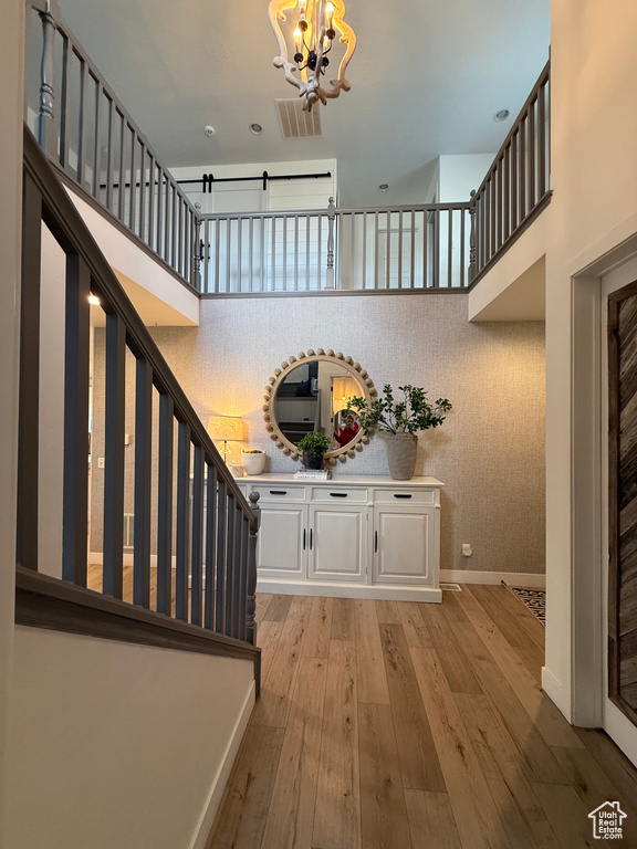 Staircase featuring a chandelier, wood-type flooring, baseboards, and a towering ceiling