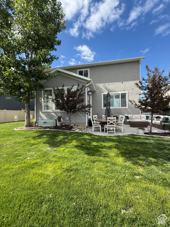 Rear view of house featuring a patio area, stucco siding, and an outdoor living space