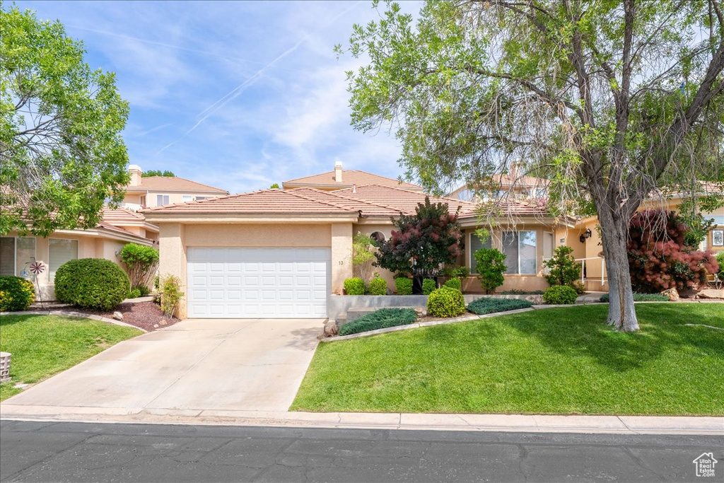 View of front of home with an attached garage, a front lawn, driveway, and stucco siding