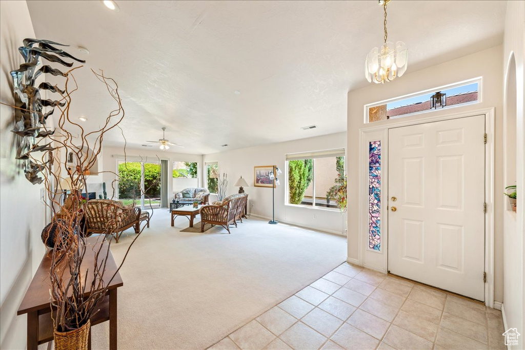 Entryway featuring light colored carpet, a chandelier, light tile patterned floors, ceiling fan, and baseboards