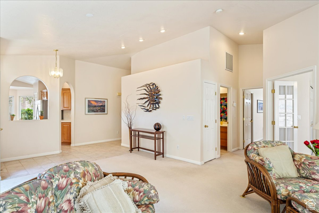 Living area with arched walkways, recessed lighting, baseboards, a high ceiling, and light carpet