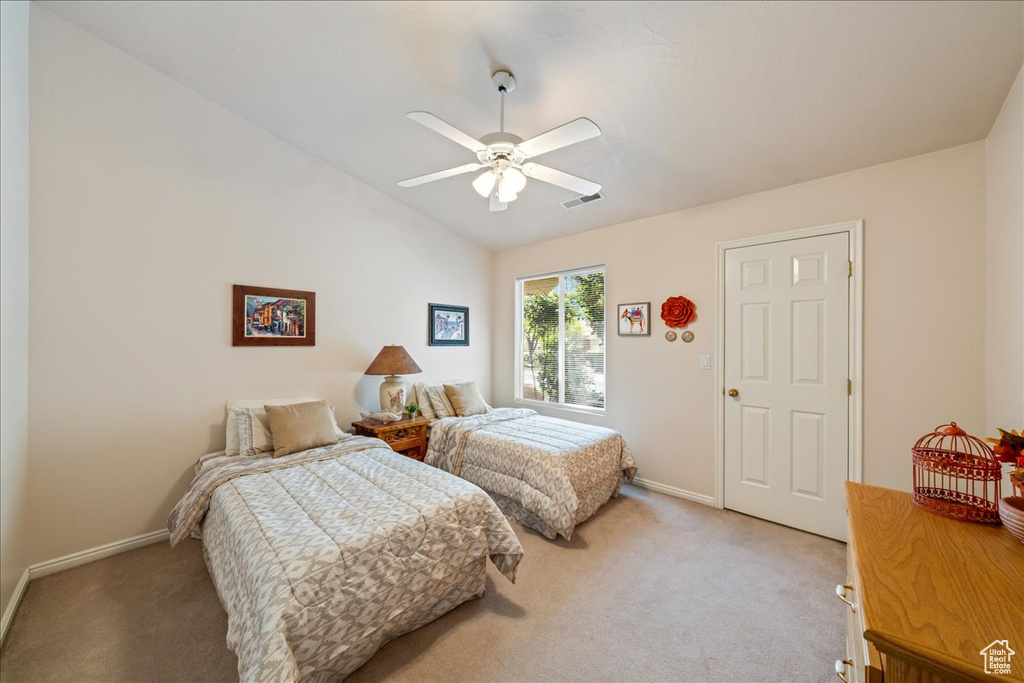 Bedroom featuring light carpet, baseboards, vaulted ceiling, and a ceiling fan