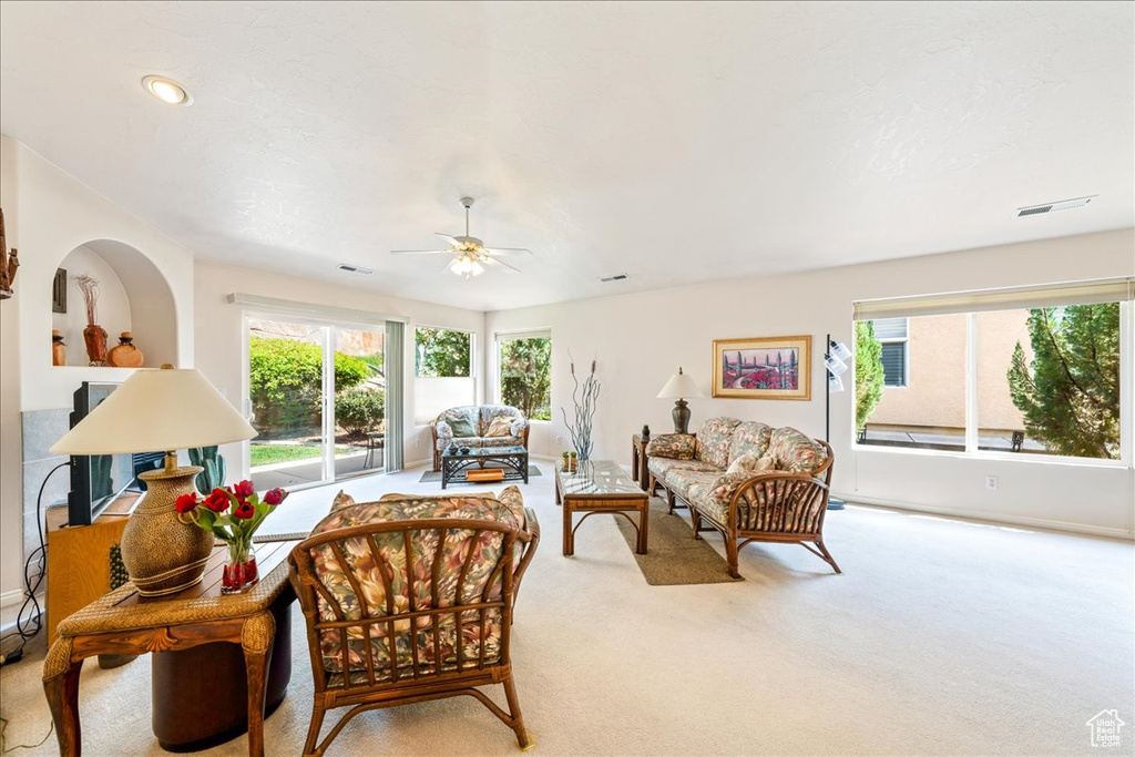 Living area featuring plenty of natural light, carpet, ceiling fan, and baseboards