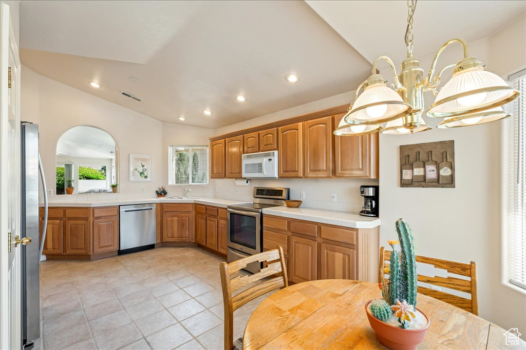 Kitchen with stainless steel appliances, vaulted ceiling, a chandelier, recessed lighting, and arched walkways