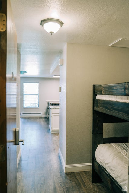 Hall featuring a textured ceiling, baseboards, wood finished floors, and a baseboard radiator