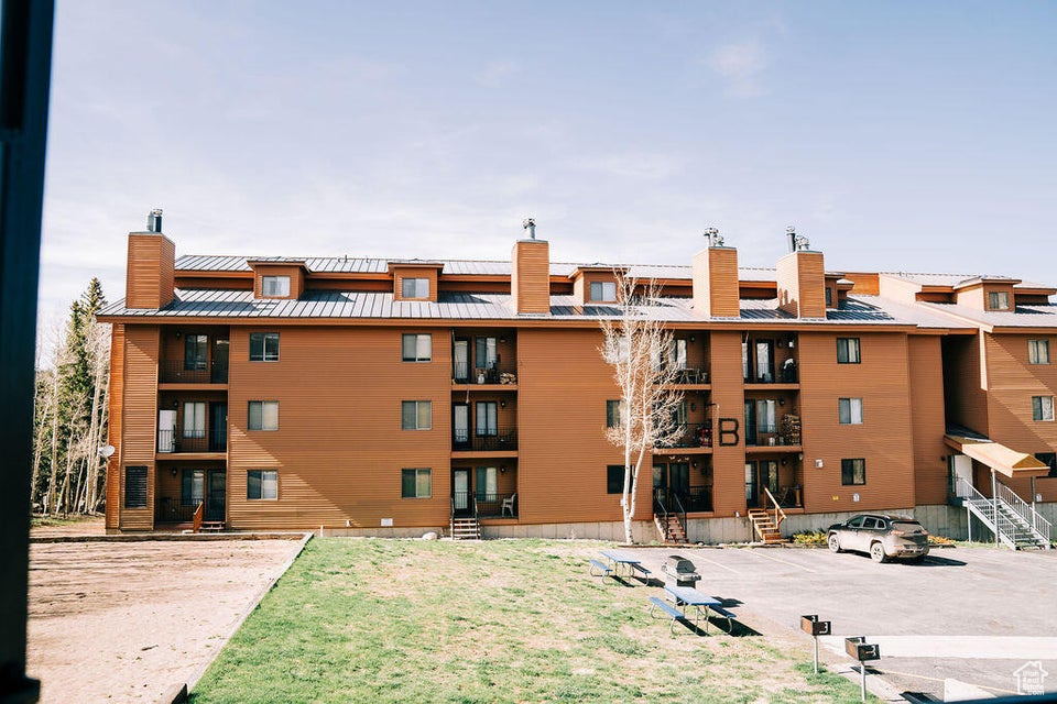 View of apartment building / complex featuring uncovered parking