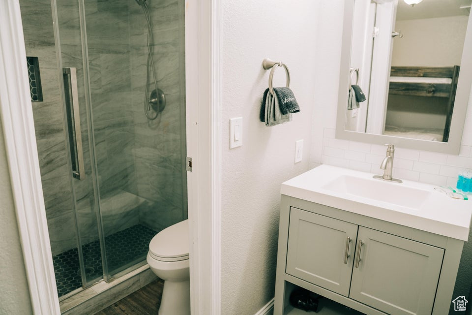 Bathroom featuring vanity, a stall shower, toilet, and decorative backsplash