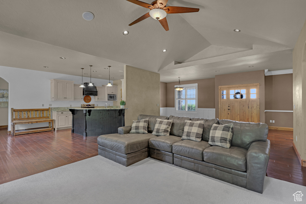 Living room featuring dark wood-style flooring, ceiling fan, recessed lighting, arched walkways, and vaulted ceiling