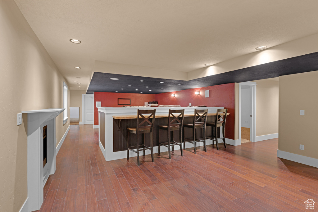 Kitchen featuring recessed lighting, wood finished floors, baseboards, a peninsula, and a breakfast bar area