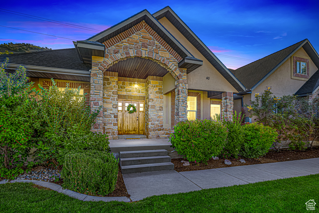 Property entrance with stone siding, stucco siding, and roof with shingles