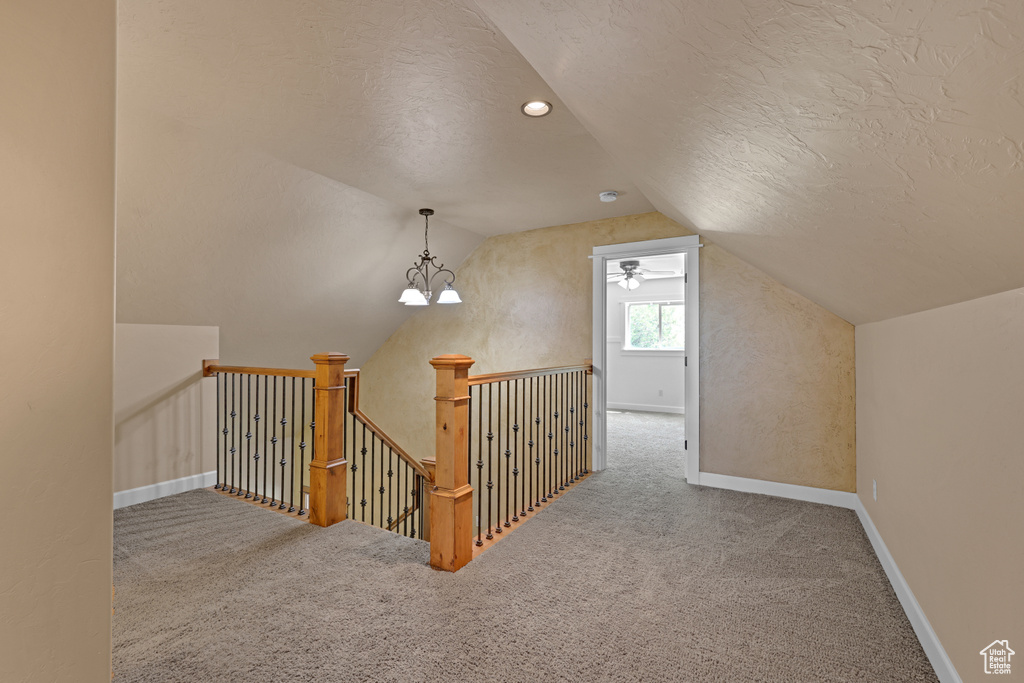 Bonus room featuring lofted ceiling, carpet flooring, a textured ceiling, and baseboards