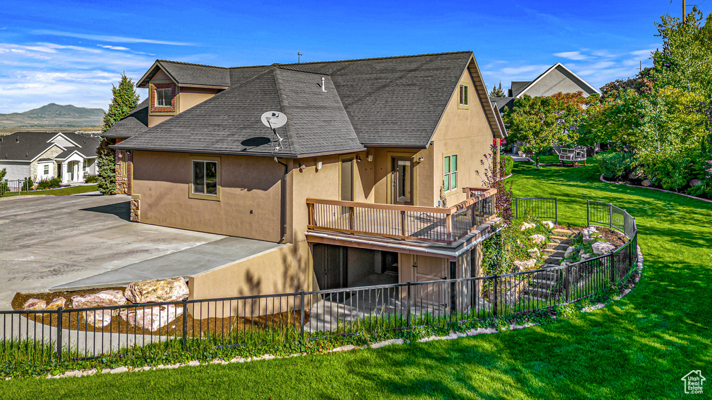 Back of house with stucco siding, roof with shingles, and a deck with mountain view