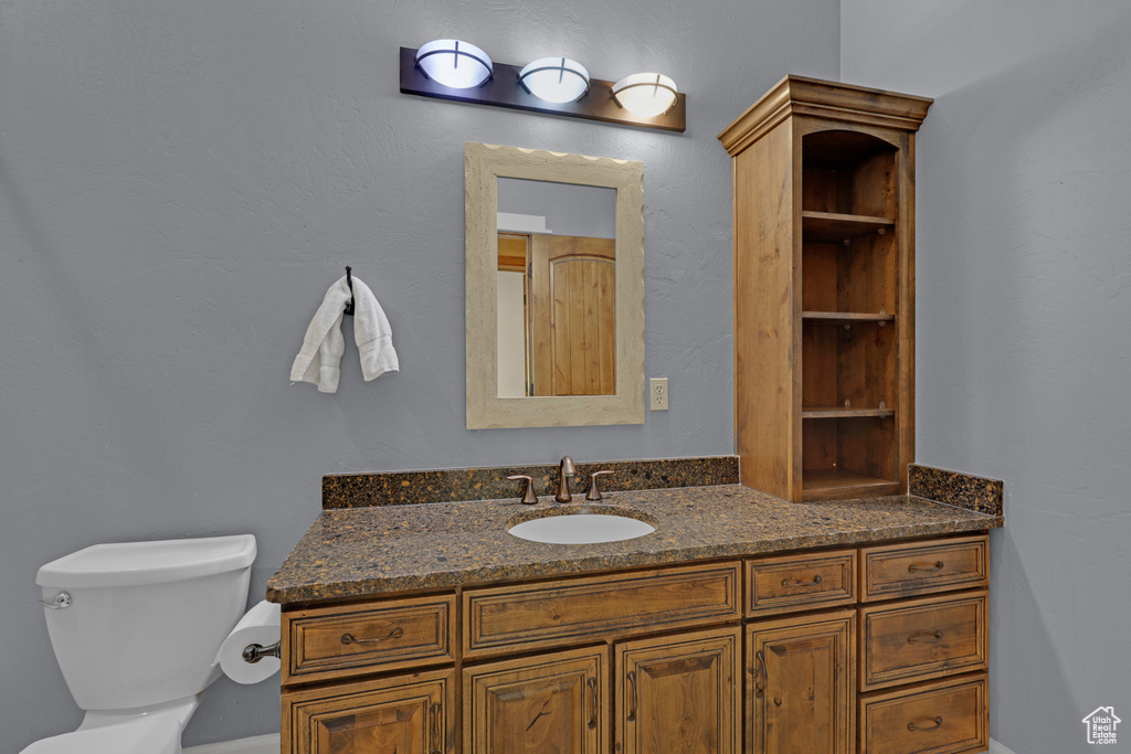Bathroom with vanity, toilet, and baseboards