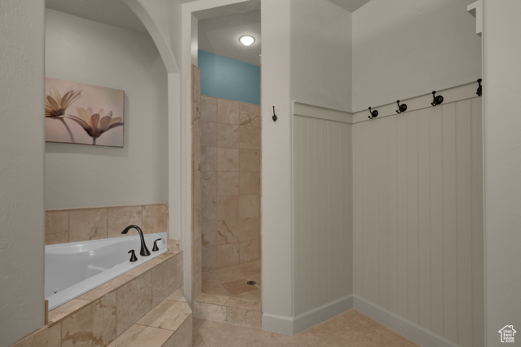 Bathroom with a bath, a tile shower, and tile patterned flooring