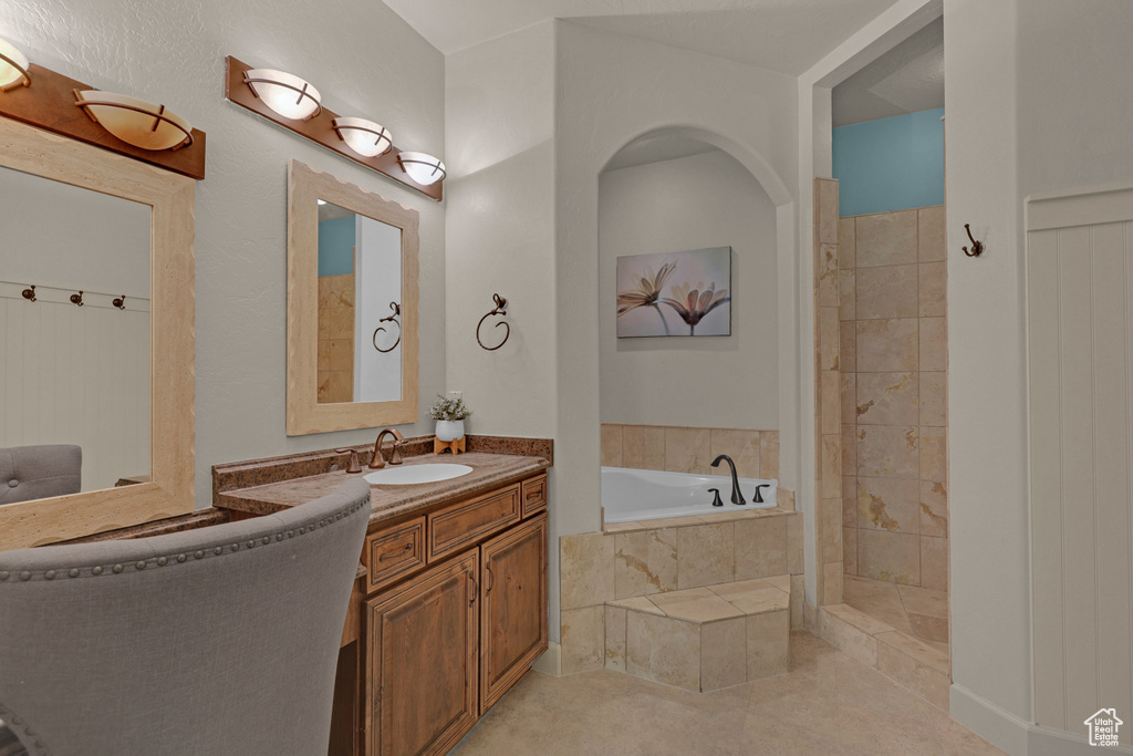 Bathroom featuring a bath, vanity, tile patterned floors, and tiled shower