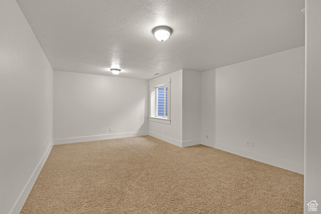 Spare room with a textured ceiling, light carpet, and baseboards