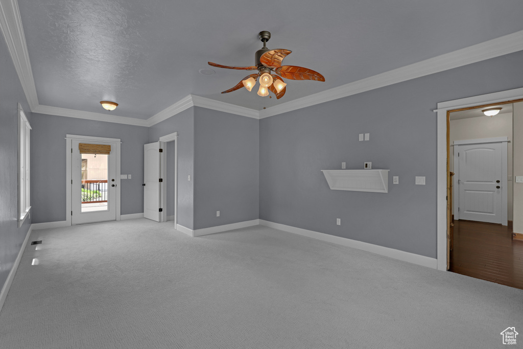 Carpeted spare room with a ceiling fan, baseboards, and ornamental molding