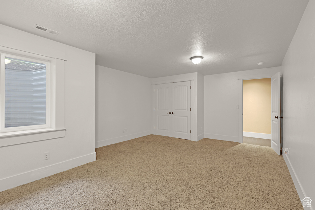 Unfurnished bedroom featuring a textured ceiling, carpet flooring, baseboards, and a closet