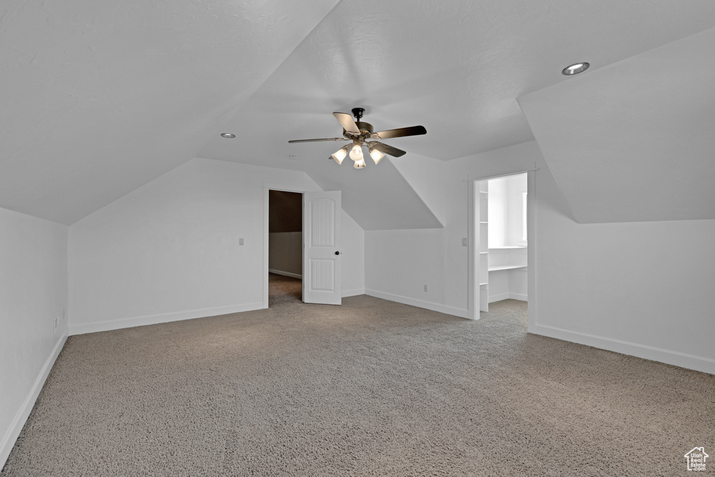 Additional living space featuring lofted ceiling, ceiling fan, carpet flooring, and baseboards