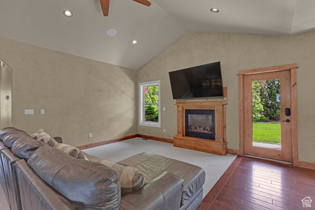 Living room featuring lofted ceiling, ceiling fan, a glass covered fireplace, recessed lighting, and baseboards