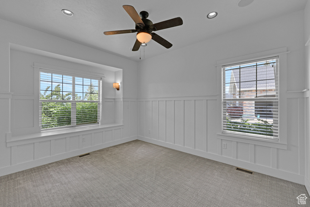 Unfurnished room featuring a decorative wall, carpet, plenty of natural light, recessed lighting, and a wainscoted wall