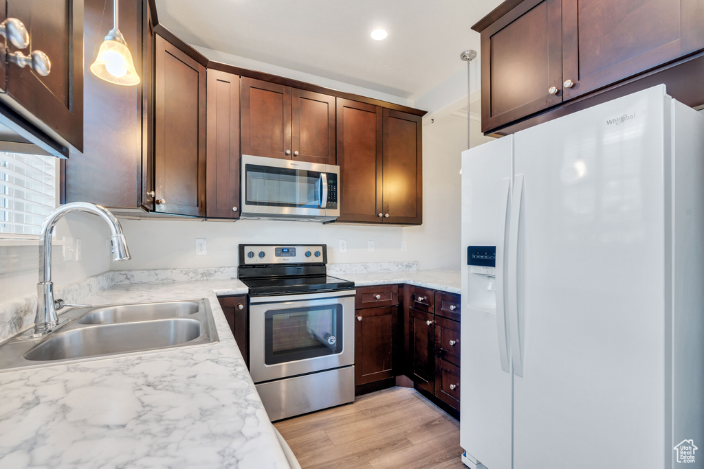 Kitchen featuring appliances with stainless steel finishes, a sink, light countertops, light wood-style floors, and recessed lighting