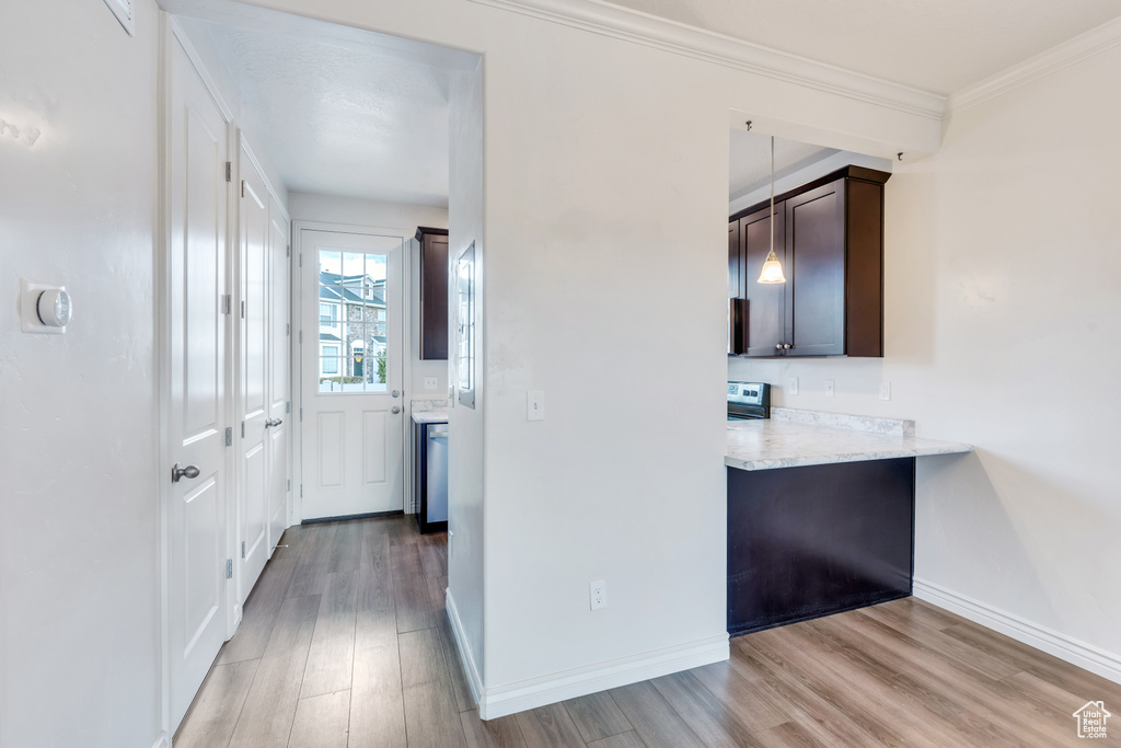 Corridor featuring light wood finished floors, baseboards, and crown molding
