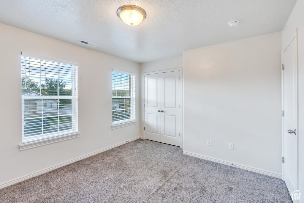 Unfurnished bedroom with carpet flooring, baseboards, a textured ceiling, and a closet