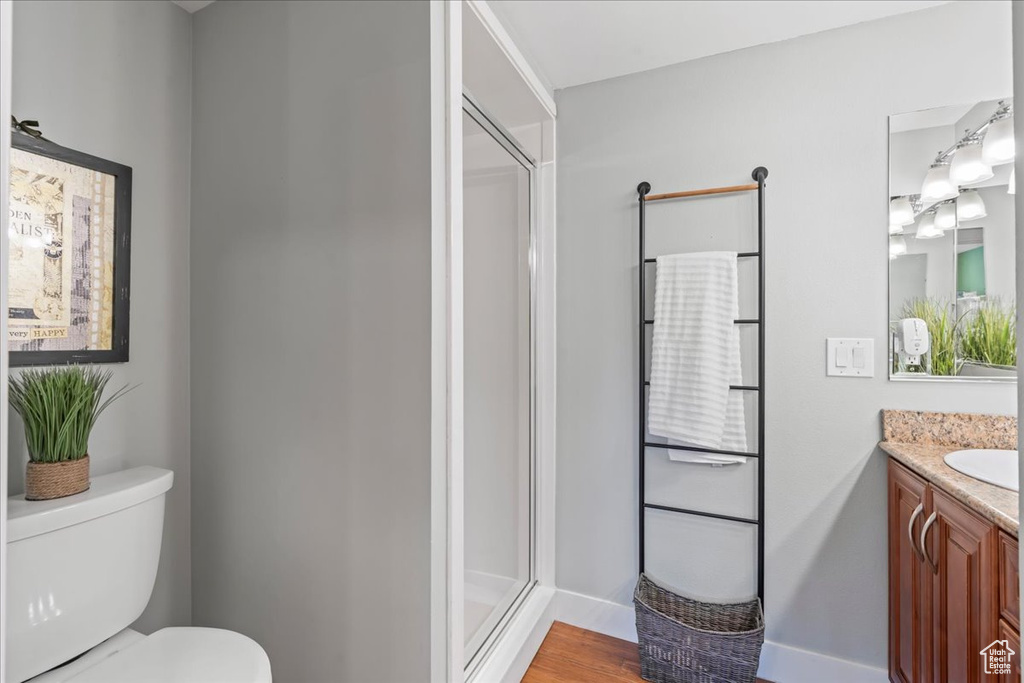 Bathroom featuring vanity, toilet, a stall shower, baseboards, and wood finished floors