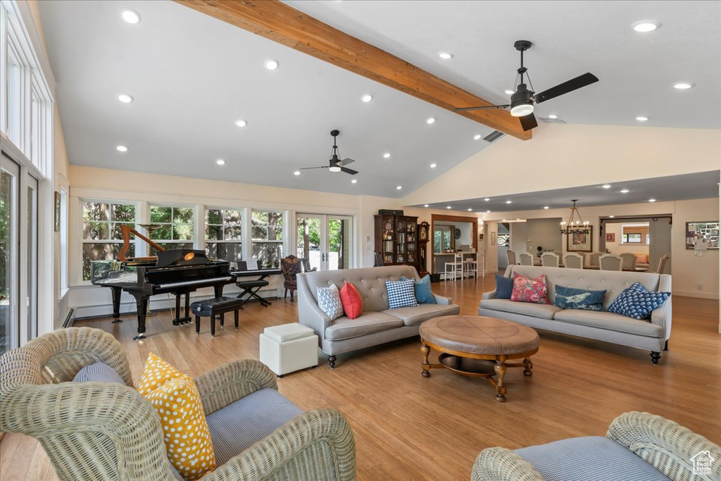 Living area featuring beam ceiling, a ceiling fan, light wood-style floors, high vaulted ceiling, and healthy amount of natural light
