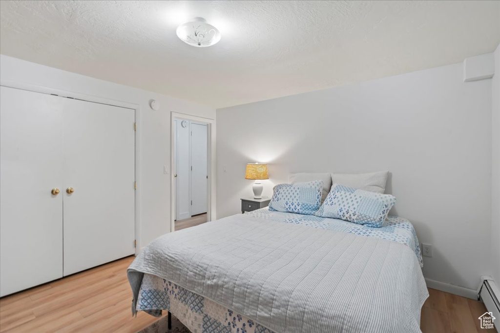 Bedroom with baseboard heating, wood finished floors, and baseboards