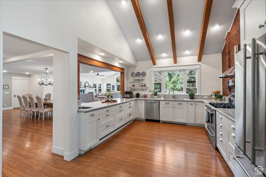 Kitchen featuring high quality appliances, a sink, light wood-style floors, beamed ceiling, and a chandelier