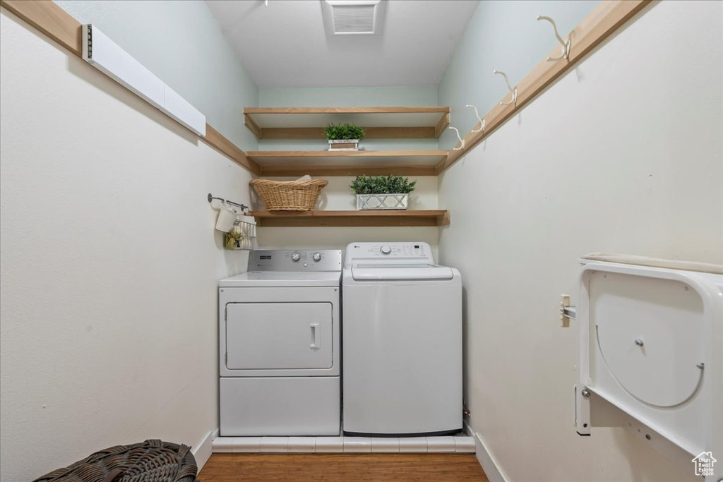 Laundry room featuring washing machine and dryer, wood finished floors, and baseboards