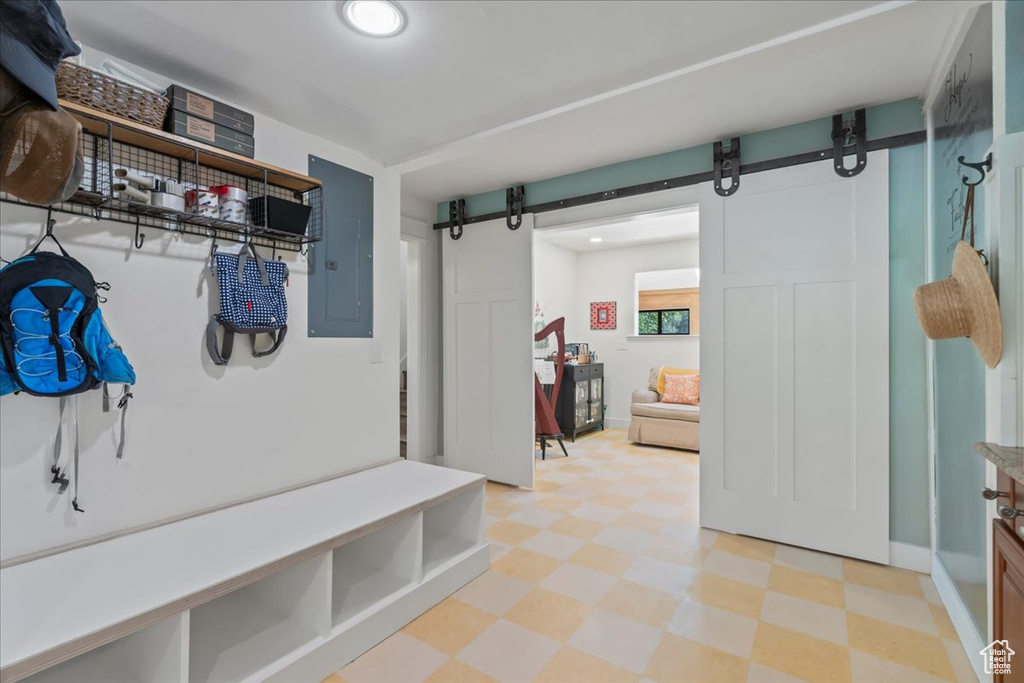 Mudroom with a barn door, light flooring, electric panel, recessed lighting, and baseboards