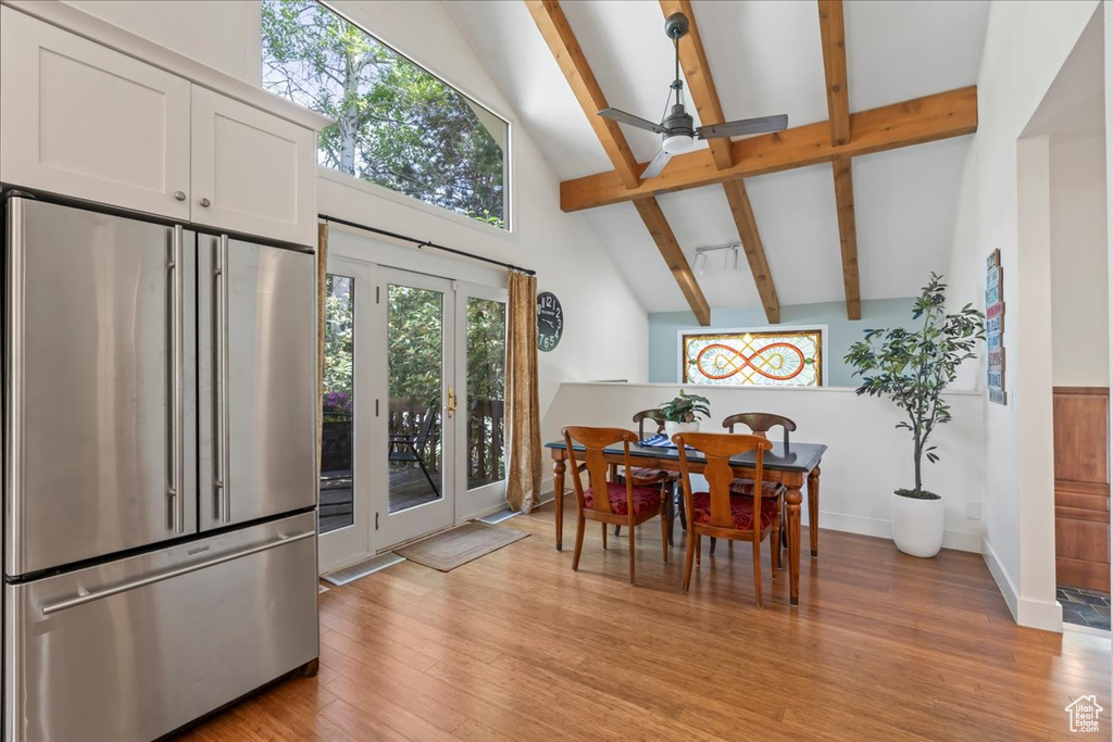 Dining area featuring beam ceiling, ceiling fan, high vaulted ceiling, light wood-style floors, and baseboards