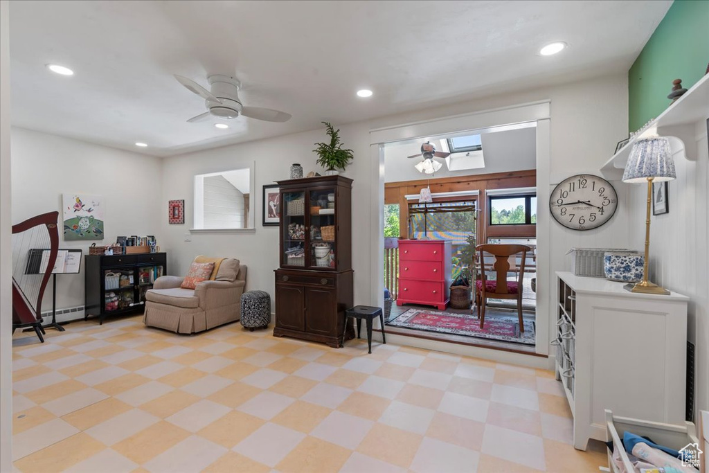 Sitting room with ceiling fan, light flooring, recessed lighting, a skylight, and a baseboard heating unit
