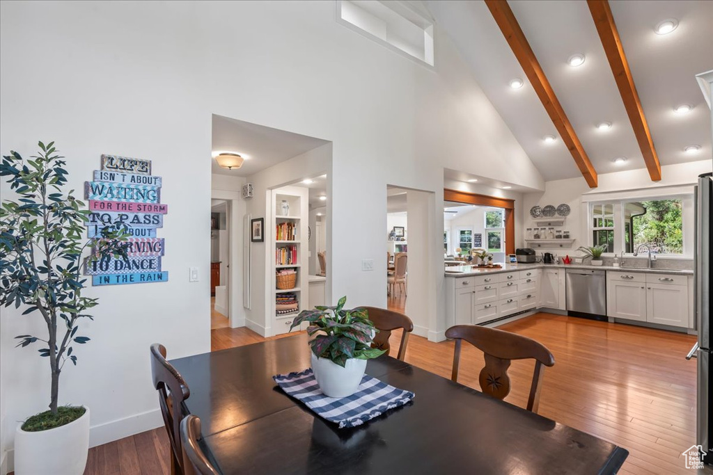 Dining room featuring light wood-style floors, beam ceiling, baseboards, high vaulted ceiling, and recessed lighting