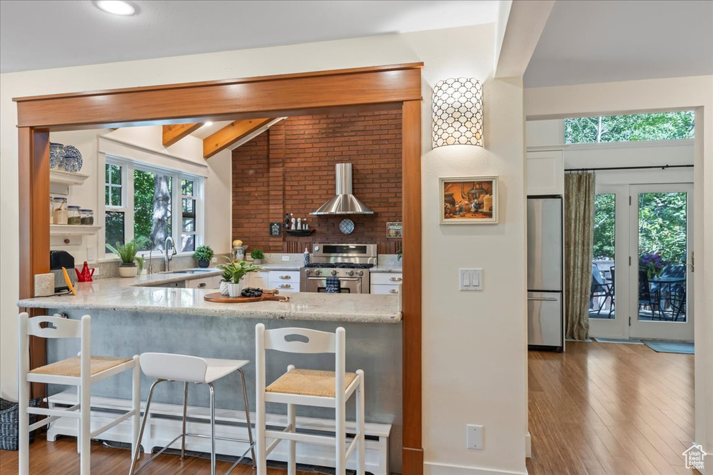 Kitchen with stainless steel appliances, a sink, extractor fan, wood finished floors, and a breakfast bar area