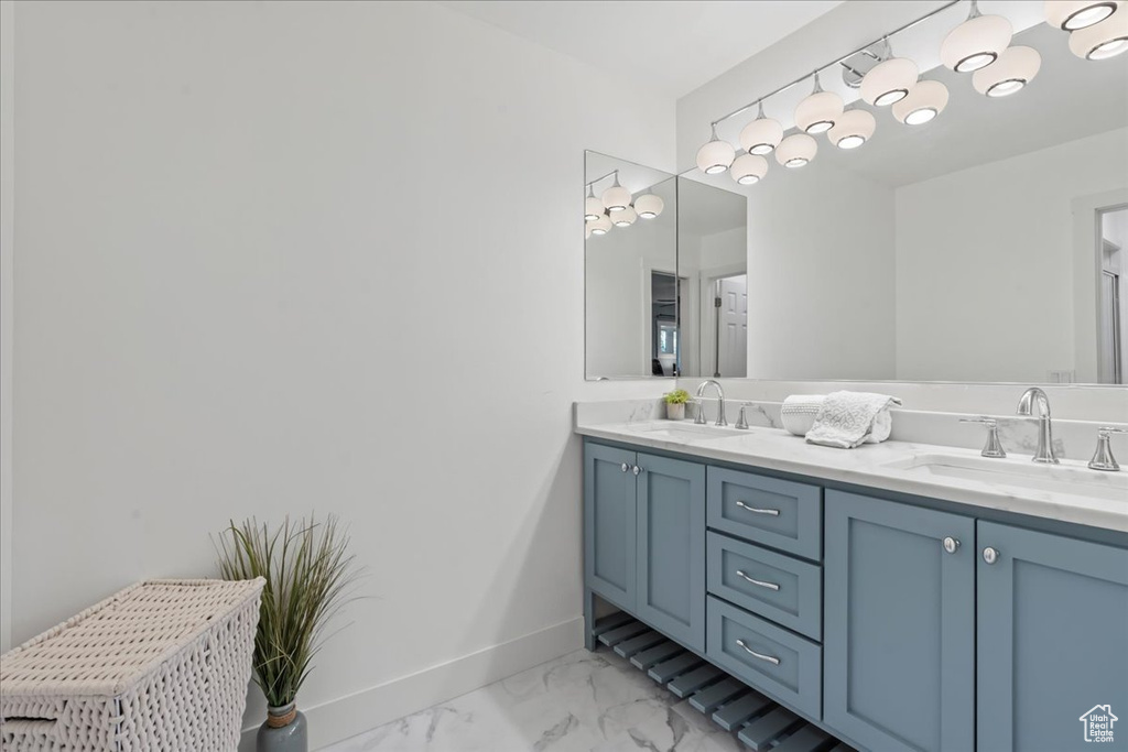 Bathroom featuring double vanity, marble look tile flooring, and baseboards
