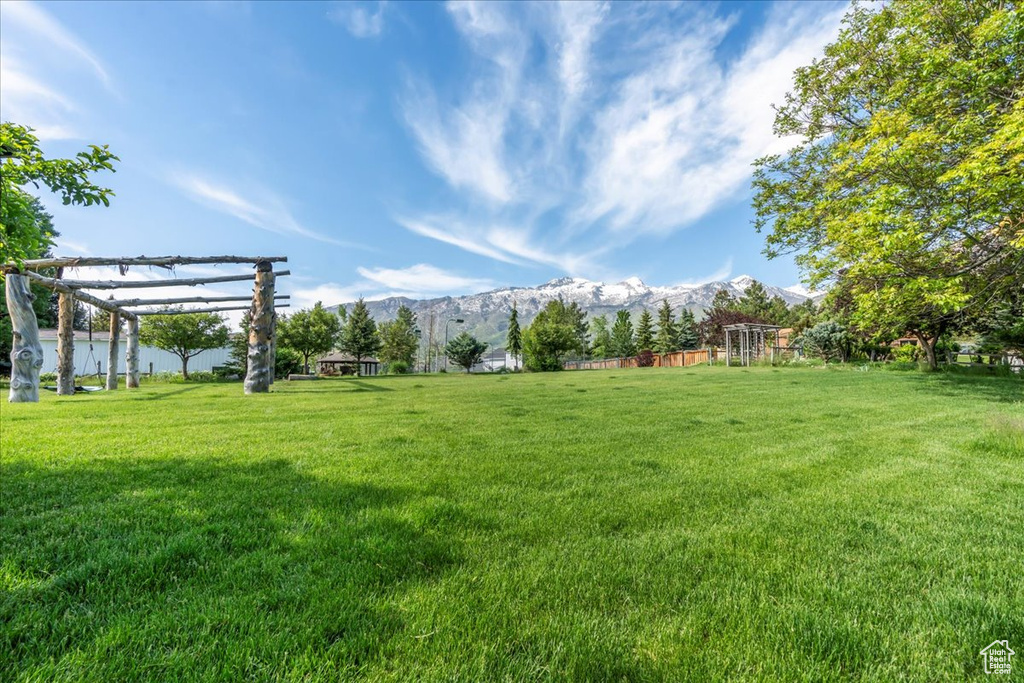 View of grassy yard featuring a mountain view and a pergola