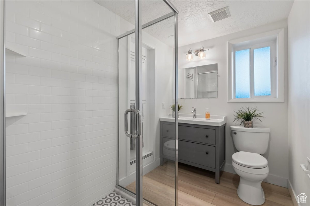 Full bath featuring toilet, vanity, a stall shower, wood finished floors, and a textured ceiling