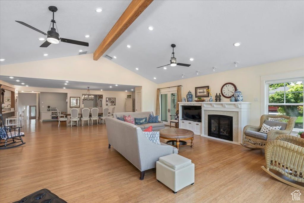 Living area with a ceiling fan, beamed ceiling, light wood finished floors, a glass covered fireplace, and recessed lighting