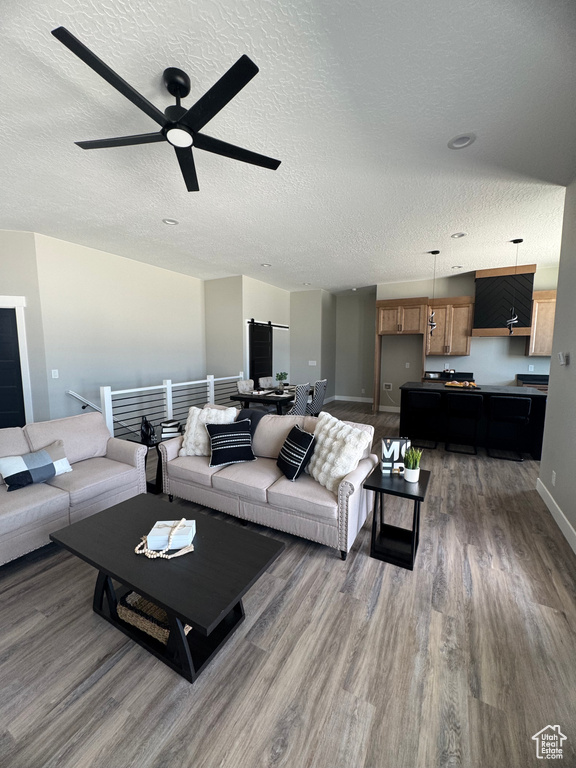 Living area with wood finished floors, a textured ceiling, baseboards, and ceiling fan
