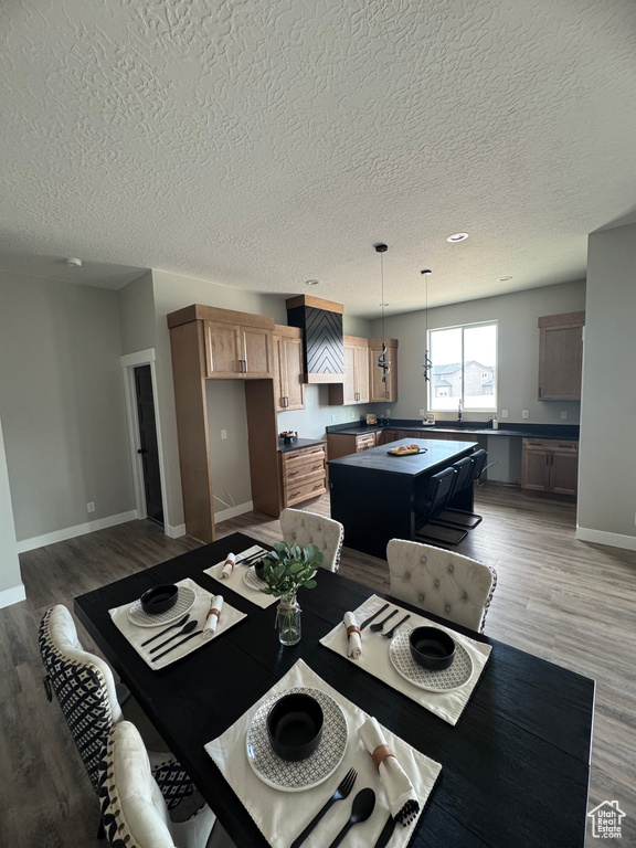 Dining space with a textured ceiling, light wood finished floors, and baseboards