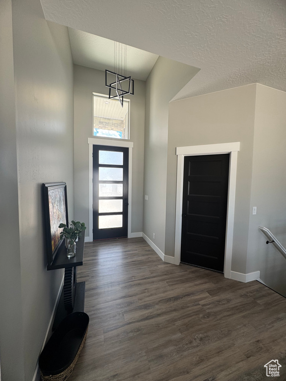 Entrance foyer with dark wood-type flooring, baseboards, a chandelier, and a towering ceiling