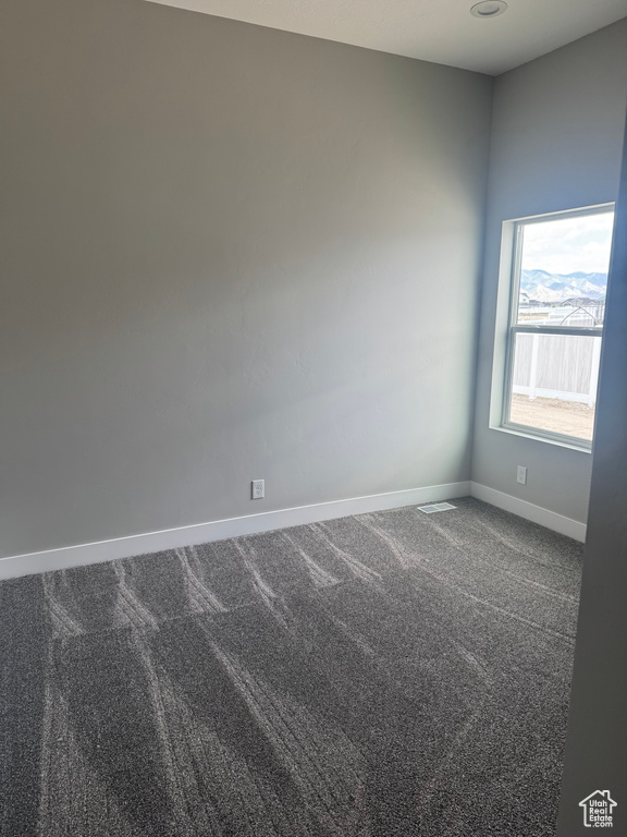 Spare room featuring dark colored carpet and baseboards