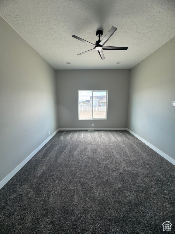 Empty room with ceiling fan, a textured ceiling, carpet flooring, and baseboards