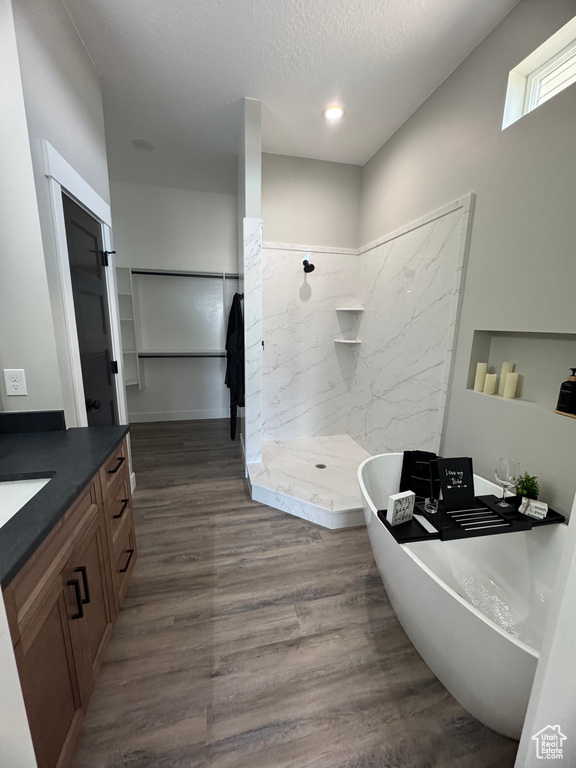 Full bath featuring a marble finish shower, vanity, a freestanding tub, wood finished floors, and a textured ceiling