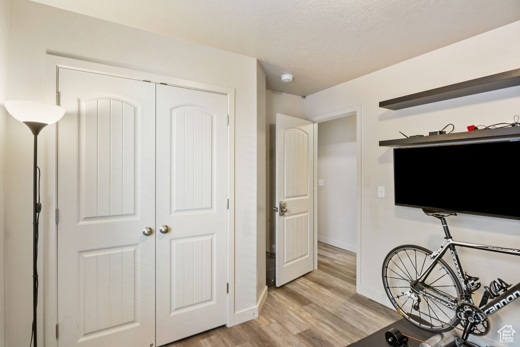 Bedroom with light wood-style floors, baseboards, and a closet